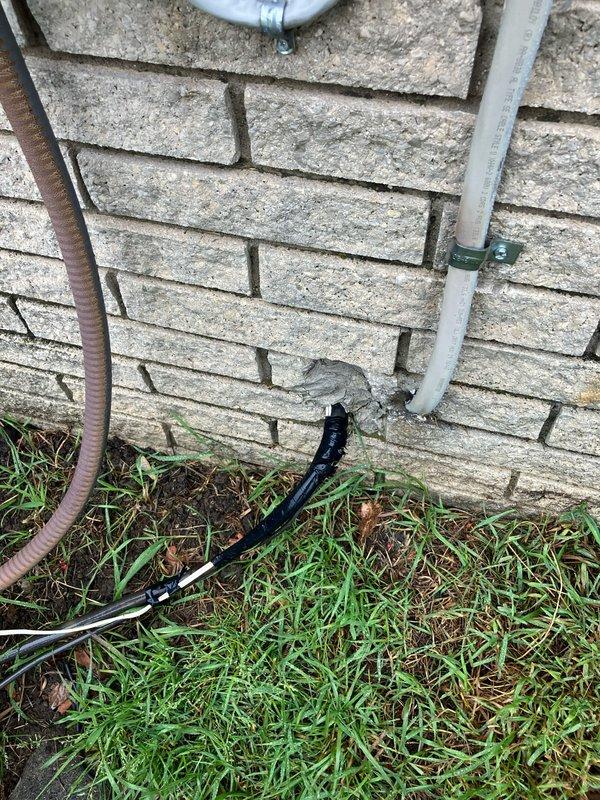 Conducted comprehensive evaluation of 15-22 year old residential air conditioning system experiencing cooling failure. Diagnosed multiple critical issues including low refrigerant charge, blown electrical fuse, and damaged wiring in basement-mounted equipment. System exhibited freezing condition due to compromised cooling capacity. Assessed exterior condensing unit with beige metal casing and copper fan assembly mounted on foundation pad alongside brick wall exterior. Evaluated electrical conduit routing, junction boxes, and power supply connections. Provided detailed replacement estimate for aging HVAC system due to cumulative component failures and overall equipment condition. Documented existing installation configuration including PVC drainage, flexible conduit runs, and utility infrastructure mounting. Recommended full system replacement as most viable solution given equipment age and extent of required repairs.