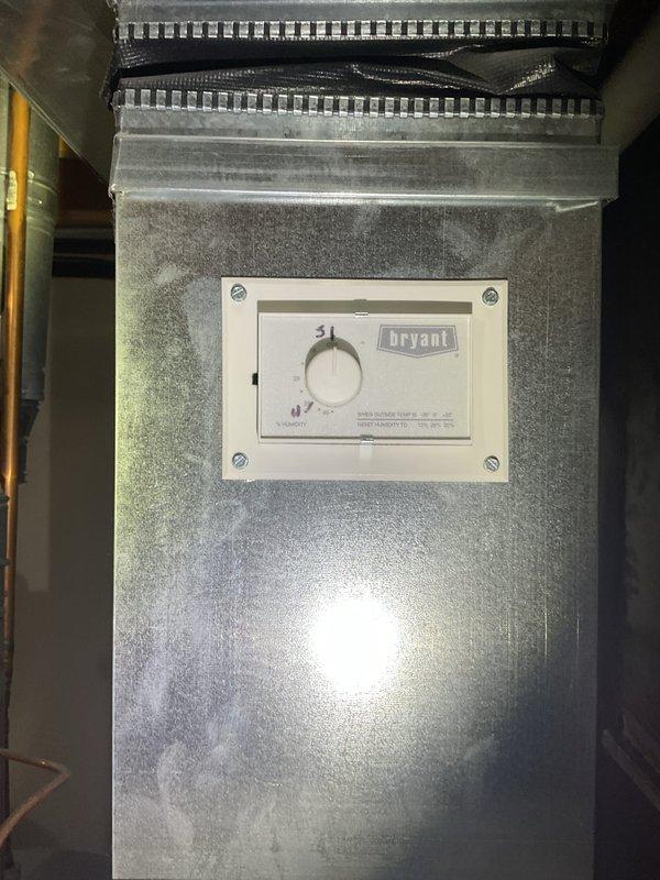 Completed Gold AC Inspection on a 10+ year old Bryant air conditioning system with air handler located in basement. Performed comprehensive system evaluation including visual inspection of equipment, verification of operational status, and documentation of unit specifications. Inspected R-410A refrigerant system with POE oil as indicated on manufacturer labels. All equipment found to be in working condition at time of inspection. Photographed unit identification labels, control panel with thermostat dial, and flexible ductwork connections for service records.