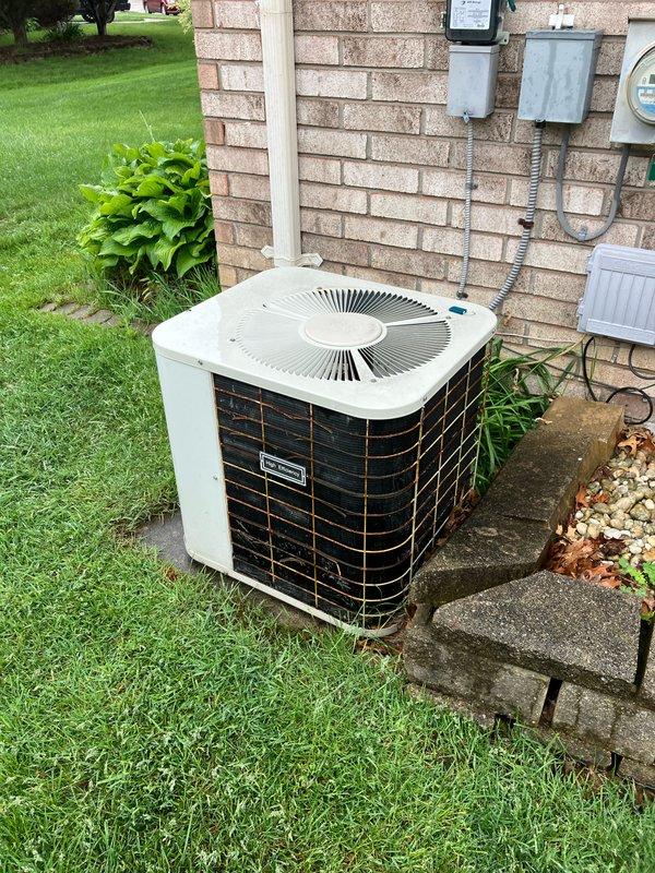 Responded to service call for air conditioning system blowing warm air. Upon inspection, diagnosed compressor failure on 1991 AC unit located in basement. Provided comprehensive replacement estimate for new air conditioning system. Documented existing outdoor condensing unit with protective cage mounted on concrete pad, electrical metering configuration, and overall installation setup through photographic documentation to support replacement recommendations.