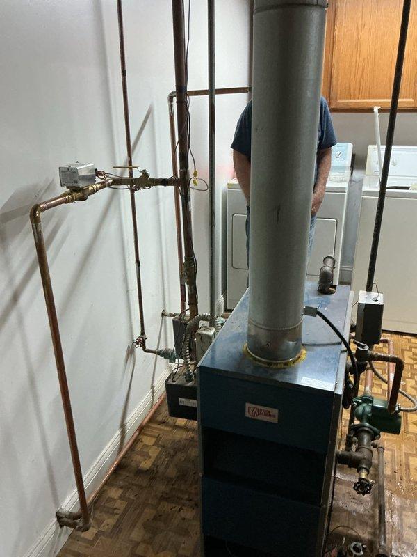 Responded to service call for 15-year-old residential boiler system located in basement. Upon arrival, performed comprehensive system inspection and diagnostic evaluation of boiler unit, associated copper piping, circulation components, and control systems. Identified temperature pressure sensor issue requiring replacement, with part ordered under purchase order for installation. Inspected Resideo control panel, verified electrical connections, and examined all plumbing connections including shut-off valves and pressure monitoring devices. Evaluated flue pipe assembly and ventilation components for proper operation. Documented system condition through photographic records showing boiler unit, piping configuration, circulation pump, and control components. System remained operational throughout service visit, continuing to provide heat while awaiting sensor replacement to resolve reported issue and restore full functionality.