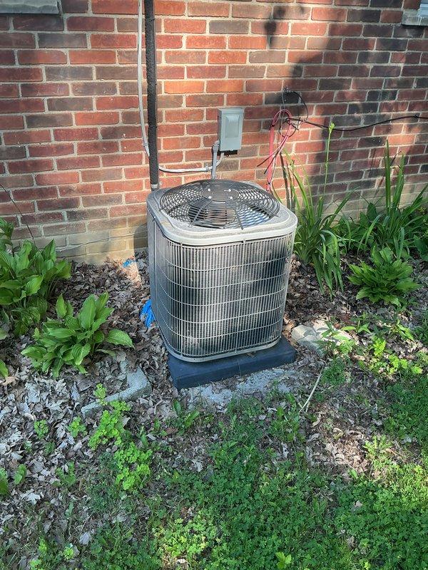 Completed comprehensive Gold AC inspection on 9-year-old residential air conditioning system. Inspected outdoor condenser unit positioned against exterior brick wall, verified proper operation of fan assembly and compressor, checked electrical connections and disconnect box, and examined refrigerant lines. Air handler located in interior closet was inspected for proper airflow and component function. Advised customer to maintain clear area around condenser unit, removing debris and vegetation encroaching on unit perimeter to ensure adequate airflow and system efficiency. Documented equipment condition with photographic records showing unit surrounded by landscaping materials and decorative stone. System operating within normal parameters at time of inspection.
