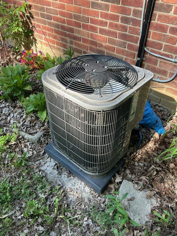 Completed comprehensive Gold AC inspection on 9-year-old residential air conditioning system. Inspected outdoor condenser unit positioned against exterior brick wall, verified proper operation of fan assembly and compressor, checked electrical connections and disconnect box, and examined refrigerant lines. Air handler located in interior closet was inspected for proper airflow and component function. Advised customer to maintain clear area around condenser unit, removing debris and vegetation encroaching on unit perimeter to ensure adequate airflow and system efficiency. Documented equipment condition with photographic records showing unit surrounded by landscaping materials and decorative stone. System operating within normal parameters at time of inspection.