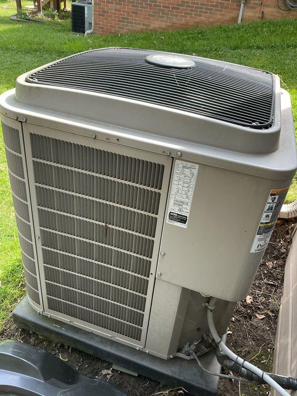 Completed comprehensive Gold AC Inspection on a 10+ year old residential air conditioning system with outdoor condenser unit and basement-located air handler. Performed thorough examination of condenser unit including inspection of cabinet condition, protective top grille, condenser coil fins, refrigerant line connections, and mounting pad stability. Unit found to be operational with normal weathering consistent with age, intact protective components, and condenser coils in reasonable condition without major deformation.