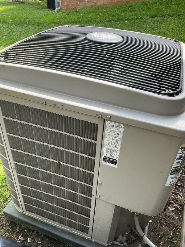 Completed comprehensive Gold AC Inspection on a 10+ year old residential air conditioning system with outdoor condenser unit and basement-located air handler. Performed thorough examination of condenser unit including inspection of cabinet condition, protective top grille, condenser coil fins, refrigerant line connections, and mounting pad stability. Unit found to be operational with normal weathering consistent with age, intact protective components, and condenser coils in reasonable condition without major deformation.