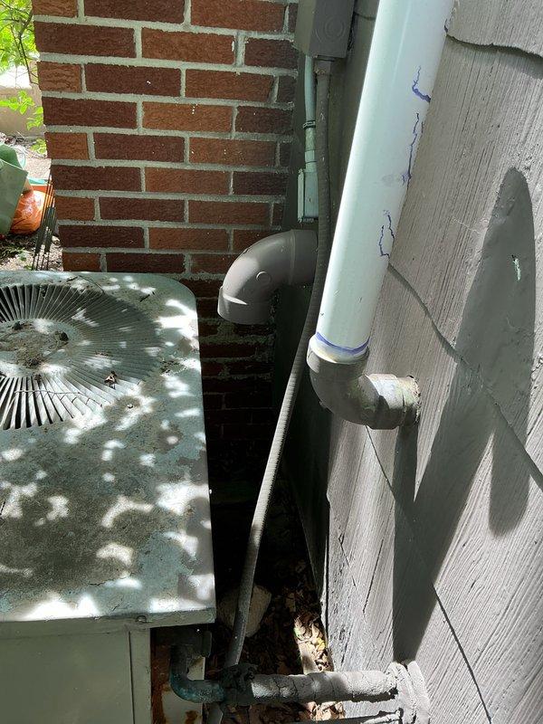 Completed HVAC estimate for cooling system replacement at residential property with small square footage (0-1500 sq ft). Assessed existing outdoor condenser unit located in side yard landscaped area and basement unit configuration. Documented current system condition including weathered condenser with cylindrical design, PVC condensate drain lines, electrical conduit routing, and equipment positioning between brick wall and exterior siding for replacement quote preparation.