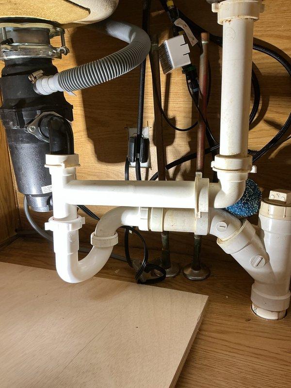 Responded to emergency plumbing call for leaking U-bend under kitchen sink in 35-year-old residence. Upon arrival, inspected PVC drain assembly and identified leak at P-trap connection point. Removed and replaced deteriorated compression gasket at U-bend joint, ensuring proper seal at all threaded connections. Verified garbage disposal drain connection and corrugated hose assembly remained secure. Tested drainage system under full water flow to confirm leak resolution. Installed drip tray beneath plumbing assembly as preventative measure. All connections tightened to specification and system restored to full operational status with no active leaks detected.