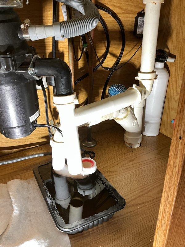 Responded to emergency plumbing call for leaking U-bend under kitchen sink in 35-year-old residence. Upon arrival, inspected PVC drain assembly and identified leak at P-trap connection point. Removed and replaced deteriorated compression gasket at U-bend joint, ensuring proper seal at all threaded connections. Verified garbage disposal drain connection and corrugated hose assembly remained secure. Tested drainage system under full water flow to confirm leak resolution. Installed drip tray beneath plumbing assembly as preventative measure. All connections tightened to specification and system restored to full operational status with no active leaks detected.