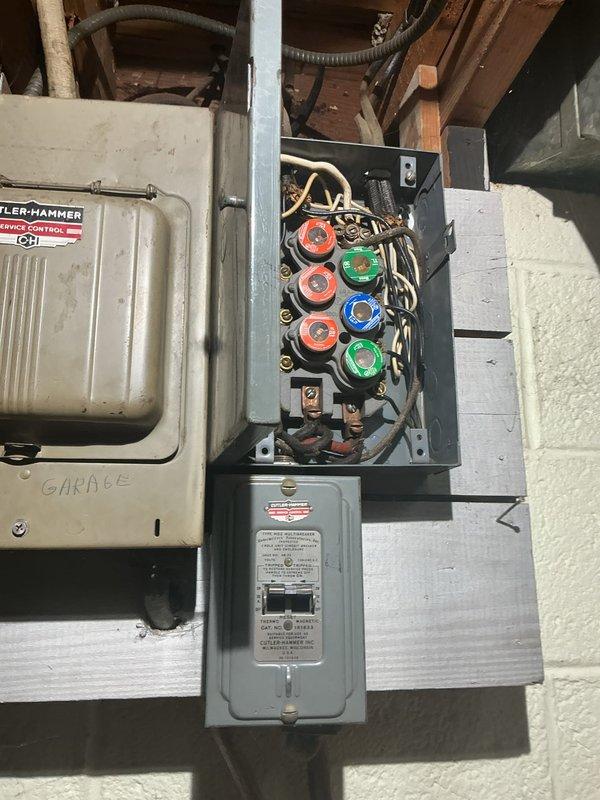 Responded to emergency service call for sparking electrical panel. Upon arrival, confirmed power had been shut off as a safety precaution. Inspected main electrical panel and fuse box assembly, identifying deteriorated connections and potential arcing at circuit breaker terminals. Found outdated fuse-style panel with compromised wiring connections causing electrical arcing. Evaluated panel condition, noting multiple colored wires (black, red, white) with signs of heat damage near connection points. Documented existing Cutler-Hammer service control equipment and circular fuse configuration in garage panel. Secured all loose connections, cleaned oxidation from contact points, and verified proper wire gauge and termination integrity throughout the panel assembly. Tested restored power supply under load to ensure safe operation without further arcing or sparking. Recommended panel upgrade to modern circuit breaker system to prevent future safety hazards.