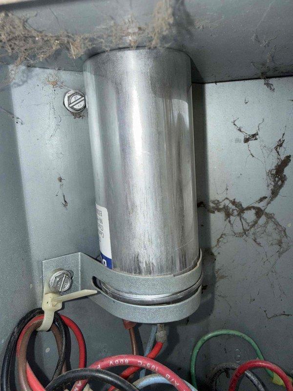 Responded to no cooling complaint on 30-year-old air conditioning system located in basement. Upon inspection, found compressor failing to engage properly, preventing refrigerant circulation and cooling capacity. Observed deteriorated electrical components with significant corrosion on mounting surfaces and control panel housing, indicating extended service life and environmental wear. Capacitor showed age-related degradation with visible rust staining on surrounding metal surfaces. Examined condensate drain connections and found accumulated debris around base assembly. System exhibited multiple signs of end-of-life condition including worn wiring connections, mineral deposits, and compromised structural integrity of cabinet components. Documented equipment condition with photographs showing corroded mounting brackets, deteriorated paint surfaces, and sediment accumulation. Due to age of equipment and extent of component failure, recommended complete system replacement rather than repa