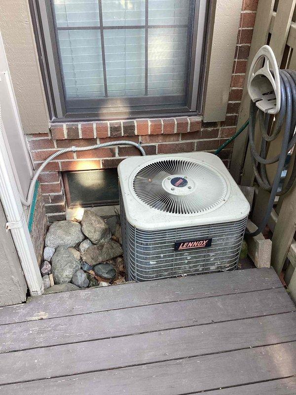 Conducted site evaluation for air conditioning replacement at residential condominium. Assessed existing Lennox condensing unit located on exterior concrete pad in confined alcove space adjacent to deck, documented installation constraints including surrounding brick walls and proximity to window. Evaluated electrical service at main panel, verified circuit capacity and existing A/C disconnect for replacement system compatibility, and provided comprehensive replacement quote for aging air conditioning system.