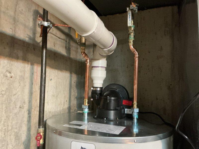 Completed installation of a 75-gallon Bradford White pressure vessel water heater in basement utility room. Connected unit to existing copper supply lines with blue-handled shut-off valves, integrated circulator pump assembly with red power switch at top of tank, and tied into overhead PVC distribution piping using appropriate fittings and transitions. Secured all piping to concrete walls with metal strapping per code requirements, verified all connections for proper operation, and ensured unit was properly labeled with installation documentation.