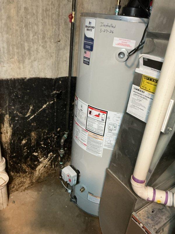 Completed installation of a 75-gallon Bradford White pressure vessel water heater in basement utility room. Connected unit to existing copper supply lines with blue-handled shut-off valves, integrated circulator pump assembly with red power switch at top of tank, and tied into overhead PVC distribution piping using appropriate fittings and transitions. Secured all piping to concrete walls with metal strapping per code requirements, verified all connections for proper operation, and ensured unit was properly labeled with installation documentation.