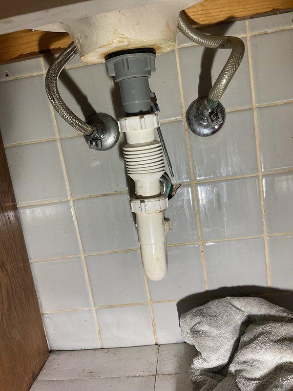 Responded to a water leak originating from bathroom sink plumbing that was penetrating through the floor into the basement below. Upon inspection, identified the source as failed connections in the drain assembly beneath the vanity. Disassembled the PVC trap and drain piping, replaced deteriorated washers and gaskets at the threaded connections, and reassembled the system with proper sealing compound. Verified supply line connections were secure and free from leaks. Tested all fixtures under full water pressure and confirmed complete resolution of the leak with no further water penetration to the lower level. Protected sink basin during repair work and left all plumbing in proper working order.