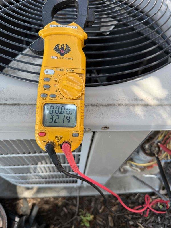 Completed comprehensive Gold AC Inspection on 10+ year old Bryant outdoor condensing unit at residential property. Performed visual inspection of exterior condenser unit positioned on concrete pad against building foundation, confirming proper clearance and adequate airflow around equipment. Utilized digital clamp meter to measure electrical parameters including voltage and amperage draw at condensing unit, verifying proper electrical function and system performance. Inspected condenser coil fins for debris accumulation, damage, or blockage that could restrict airflow. Verified operation of condenser fan motor and compressor. Checked refrigerant line connections and electrical disconnect box mounted on exterior wall. Confirmed unit operational with no visible damage, excessive wear, or safety concerns noted. Equipment operating within normal parameters at time of inspection with air handler/coil located in basement area.