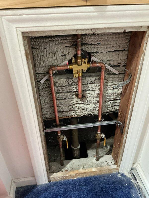 Replaced faulty shower valve and hose bib assembly in bathroom. Accessed plumbing infrastructure through wall cavity, removed existing corroded copper piping and brass valve fittings, and installed new chrome shower fixture with single-handle faucet control and tub spout. Completed installation with proper sealing and tested system for leaks to ensure proper water flow and temperature control.
