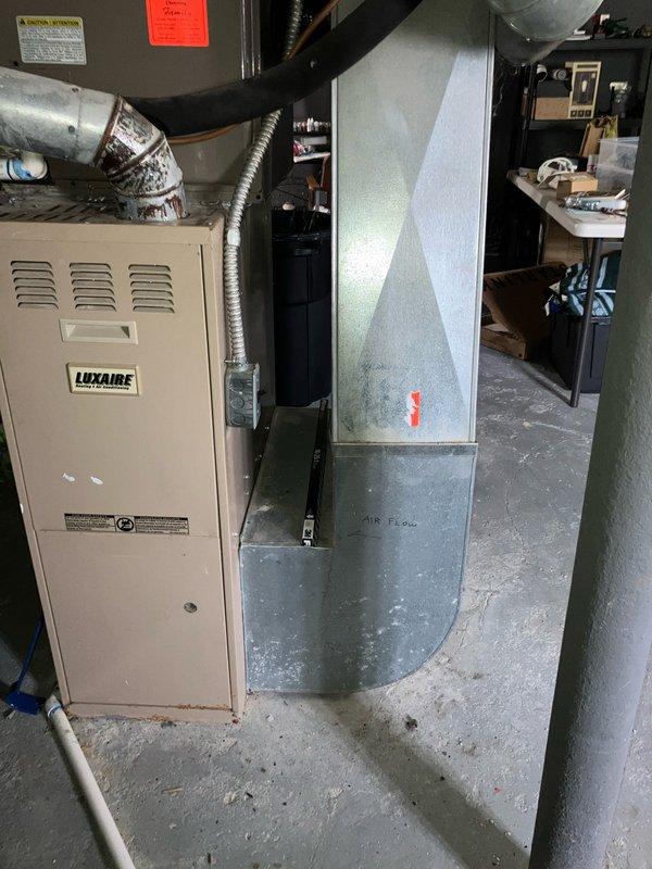 Completed furnace replacement estimate for 26-year-old Luxaire heating system located in basement. Assessed existing equipment including furnace unit with flexible metallic ductwork connections and adjacent gray metal air handler with plenum assembly. Evaluated smart thermostat compatibility and provided comprehensive replacement quote for aging HVAC system.