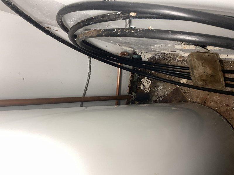 Responded to water leak in utility area with standing water on floor. Upon inspection, identified source of leak from plumbing connections near water heater. Shut off water supply using existing brass shut-off valves and assessed extent of water damage to surrounding area. Tightened loose connections on copper piping and replaced deteriorated hose clamp on water heater inlet line. Tested all connections under pressure to verify leak was resolved. Recommended follow-up maintenance to address accumulated debris and grime on mechanical components to prevent future issues.