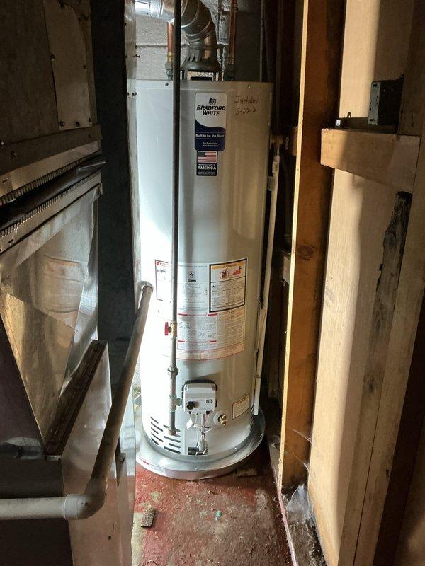 Installed a 40-gallon Bradford White natural gas water heater (Model RG240T6N) with 40,000 BTU/hr input capacity in basement utility space. Installation included drip pan with alarm system and reconnection of all gas, water, and venting components per manufacturer specifications and ASHRAE Standard 90.1 compliance requirements.