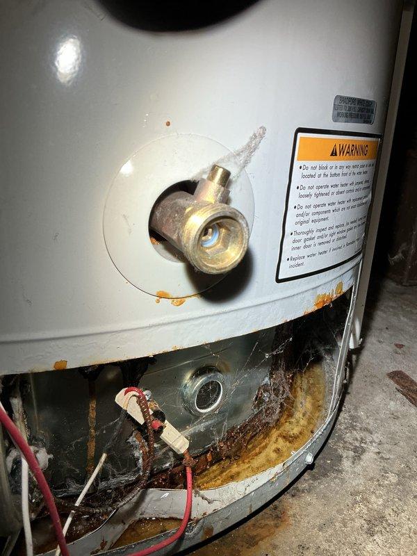 Responded to water leak emergency in basement furnace room affecting hot water supply throughout the building. Upon inspection, identified failed water heater with extensive corrosion, rust staining, and mineral deposit buildup at tank base, along with active leaking and standing water on concrete floor. The unit showed significant deterioration consistent with age-related failure, with visible water damage to the metal base plate and discharge evident around the bottom perimeter. Documented conditions with photographs showing corroded tank base, compromised structural integrity, and water accumulation. The water heater exhibited clear signs of end-of-life failure requiring replacement to restore hot water service and prevent further water damage to the basement area.