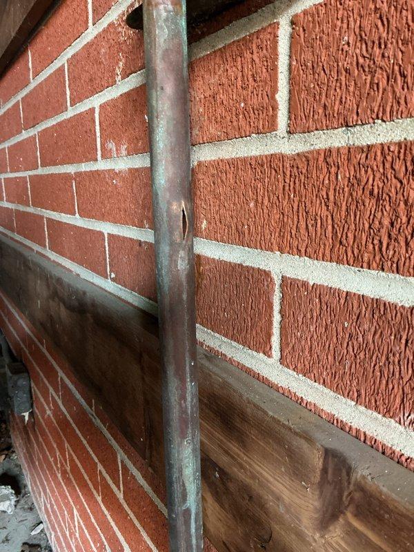 Completed warranty service for freeze-damaged plumbing components. Inspected and documented severely corroded copper piping and fittings showing extensive verdigris corrosion and deterioration from freeze break conditions. Assessed water-damaged wall surfaces with significant structural deterioration, mineral deposits, and moisture intrusion around affected plumbing installation.