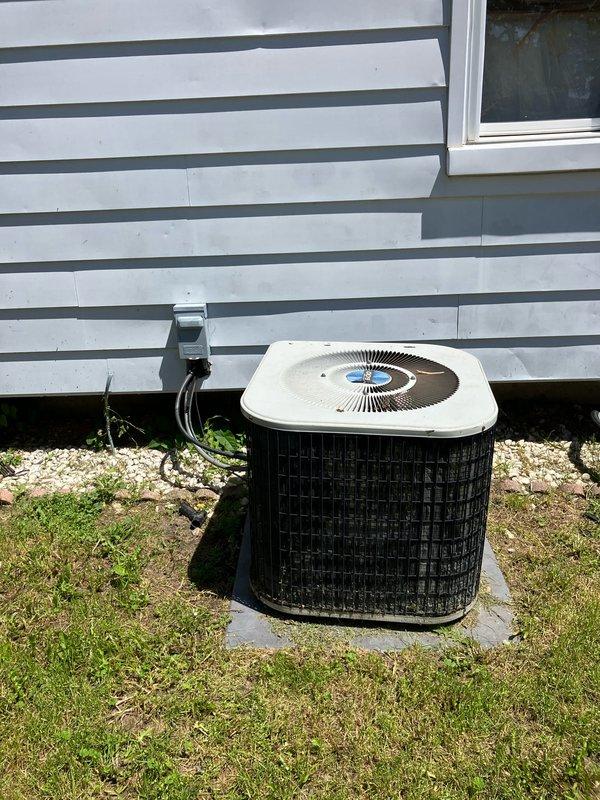 Conducted comprehensive site evaluation for complete HVAC system replacement of 20-year-old equipment with existing furnace located in basement and outdoor condensing unit positioned on concrete pad adjacent to building exterior. Documented current system configuration including electrical disconnect box, conduit routing, and equipment placement for accurate replacement specifications. Photographed existing outdoor unit installation, foundation conditions, and electrical service connections to prepare detailed replacement estimate.