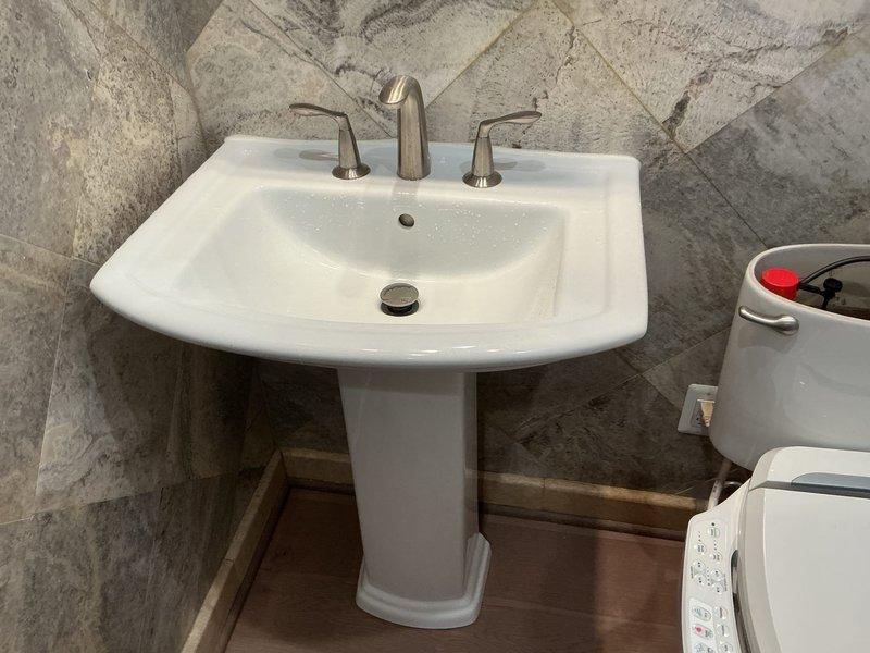 Responded to service call for pedestal sink leaking from underside. Upon inspection, identified water leak originating from supply line connections beneath the basin. Tightened compression fittings on hot and cold water supply lines and inspected drain assembly for proper seal. Verified pedestal sink mounting and checked for any cracks in porcelain fixture. Tested water flow and monitored connections under pressure to confirm leak was resolved. No further water discharge observed from underside of sink after repair completion.