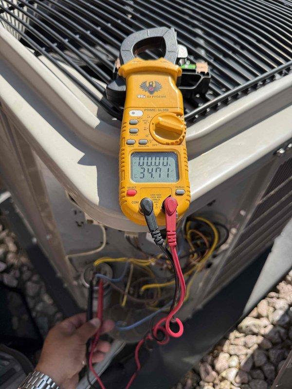Completed comprehensive Gold AC Inspection on 13-year-old air conditioning system located in basement. Performed visual inspection of outdoor condenser unit, confirming condenser coil fins in good condition with minor weathering and dirt accumulation typical for age. Utilized digital clamp meter to test and verify electrical performance, measuring amperage and voltage at condenser unit to ensure system operating within manufacturer specifications. All electrical components and wiring inspected and found functional with no immediate safety concerns identified.