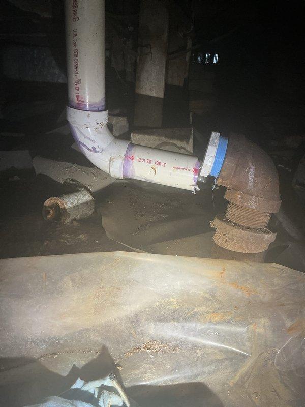 Responded to a washing machine drain line backup issue caused by slow drainage in a previously modified plumbing system. Upon arrival, inspected the basement plumbing infrastructure where the homeowner had previously cut and re-piped the capped main drain line. Identified a blockage located approximately one to two feet within the drainage pipe that was preventing proper water flow and causing backup conditions.

Examined the PVC drain line connections, including elbow joints and transitions to older metal plumbing components showing significant corrosion. Assessed the plumbing configuration in the confined utility area, noting the convergence of multiple pipe sizes and the condition of existing connections. Cleared the obstruction from the drain line to restore proper flow rate and eliminate the backup issue. Verified drainage system functionality to ensure water now flows freely through the washing machine drain without restriction. Documented existing plumbing conditions including c