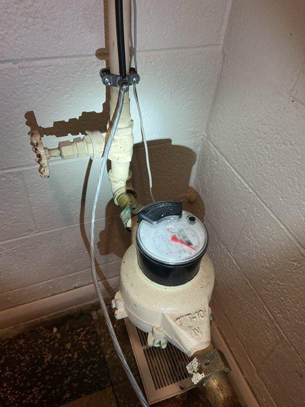 Responded to service call for slow water leak occurring at interior irrigation valve in 70-year-old home. Upon inspection, identified leak originating from aged brass valve assembly connected to outdoor irrigation system, with water dripping at rate of approximately one drop every few seconds when valve was in open position. Leak was isolated to valve stem packing and associated pipe fittings showing significant corrosion and oxidation consistent with age of plumbing system. Inspected water meter assembly and associated copper supply lines mounted on basement wall, noting advanced deterioration of valve components and compromised pipe connections. Documented existing plumbing configuration including corroded brass fittings, aged copper piping, and meter installation. Assessed condition of irrigation shutoff valve and surrounding pipe joints for extent of water damage and potential failure points. Provided customer with photographic documentation of leak source and recommendations for v