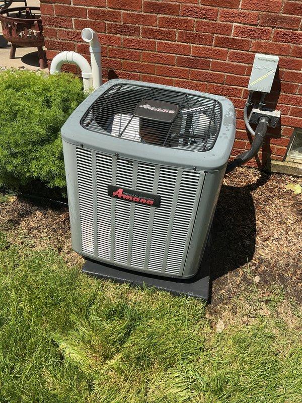 Completed comprehensive Gold AC inspection on 8-year-old Amana condensing unit located on exterior concrete pad. Performed multi-point system evaluation including visual inspection of condenser cabinet, fan grille, refrigerant line connections, electrical disconnect box, and condensate drain piping. Unit found in operational condition with proper airflow through louvers, secure mounting on pad, and adequate clearances from structure. Verified PVC condensate line routing and confirmed electrical connections at disconnect box. System operating as designed with no immediate service requirements identified during inspection.