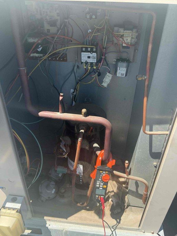 Responded to commercial facility for complaints of excessive noise from HVAC system and building pressure imbalance causing doors to blow open when units cycle. Inspected two rooftop units (RTUs) and performed diagnostic testing on electrical components and refrigerant systems. Used digital multimeter to verify proper voltage and amperage across contactors, relays, and control modules. Identified issues with system airflow balance affecting building pressurization. Examined interior components including copper refrigerant lines, valves, and air handling sections with perforated grilles. Completed electrical measurements and documented equipment conditions for both roof-mounted and ceiling units.