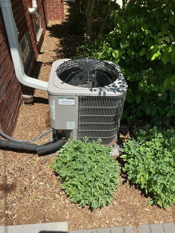 Completed Gold AC Inspection on 4-year-old single-zone residential air conditioning system with air handler located in basement. Performed comprehensive maintenance inspection including visual assessment of outdoor condensing unit, refrigerant line connections, and overall system operation. 

Addressed customer concern regarding condenser unit settlement and slope deterioration since installation. Inspected unit positioning on mulch bed alongside brick exterior, noting condensing unit placement and ground conditions. Evaluated structural stability, refrigerant line routing along exterior wall, and proper drainage considerations. Photographically documented current condenser positioning, surrounding landscape conditions, and unit installation configuration for future reference.

Verified system operational status, inspected condenser coil fins, fan assembly with protective grille, and electrical connections. Confirmed proper refrigerant line insulation and secure mounting to building ex