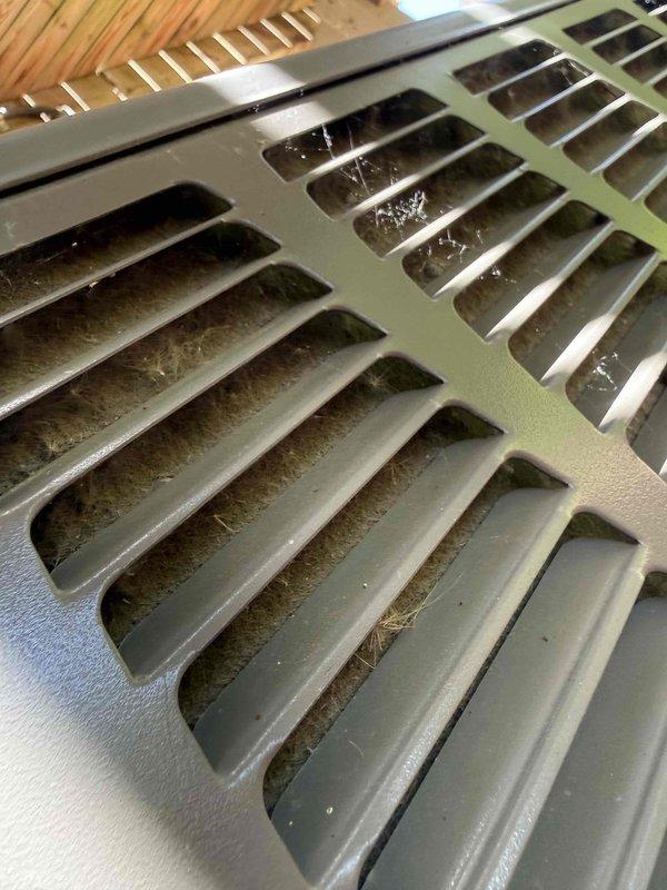 Completed comprehensive AC tune-up and cooling system maintenance on residential air conditioning unit. Performed standard inspection protocol including refrigerant level check, electrical connection testing, condenser coil cleaning, and air filter evaluation. Documented significant dust and debris accumulation on supply and return air vents with photographic evidence; noted heavy buildup of lint, cobwebs, and airborne particles restricting proper airflow through register grilles. System confirmed operational and cooling properly upon completion of maintenance procedures.