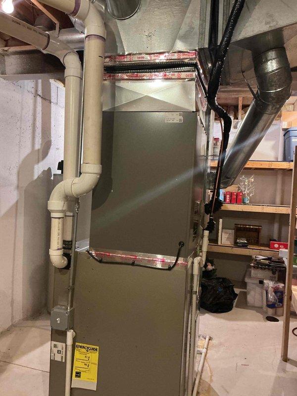 Successfully completed installation of a 5-ton air conditioning system with matching evaporator coil on the right side of the residence. Installed new outdoor condensing unit and indoor A-frame coil, establishing proper refrigerant line connections between components. Reconnected all electrical wiring to the new equipment, ensuring proper voltage and amperage to the condensing unit. Routed and secured refrigerant lines with appropriate insulation, connecting to the furnace cabinet. Verified proper condensate drainage through existing PVC piping system with multiple trap configurations. Wrapped and sealed all ductwork connections at the furnace plenum with foil tape to prevent air leakage. Tested system operation, confirming proper cooling cycle, airflow, and temperature differential across the coil. All work performed in basement mechanical room with adequate clearance maintained for future service access. Installation completed in accordance with manufacturer specifications and local 