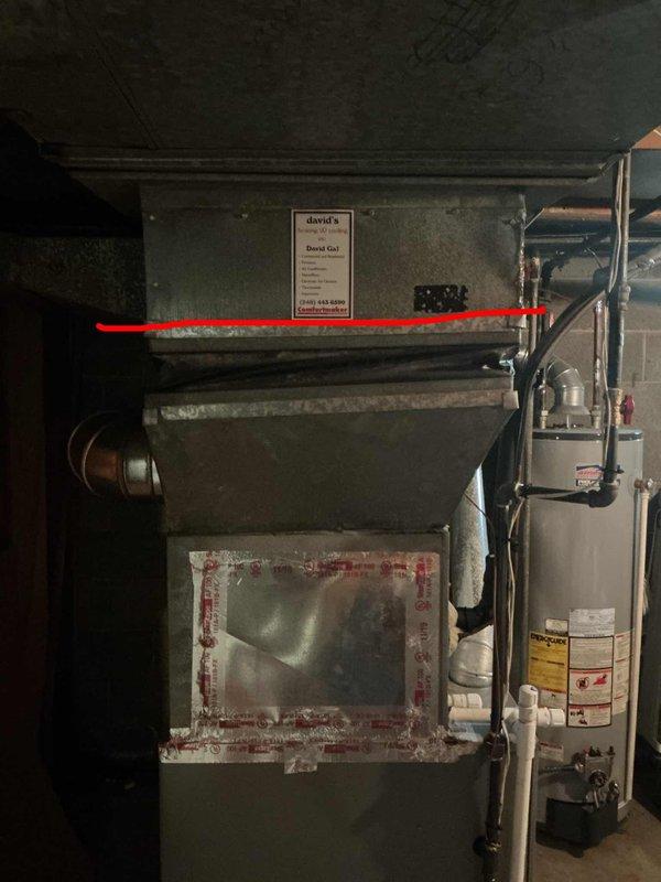 Conducted on-site evaluation of existing 32-year-old air conditioning system located on exterior side of residence to provide replacement estimate. Inspected current outdoor condensing unit and assessed overall system condition, noting equipment age has exceeded typical service life expectancy. Evaluated interior HVAC components including ductwork assembly, furnace unit with access panels, and associated mechanical connections in basement utility area. Documented existing system configuration through photographic records showing dark-colored metal ductwork, cylindrical pipe connections, and furnace equipment with transparent inspection panels. Reviewed current installation layout to determine replacement specifications and equipment requirements for new air conditioning system installation.