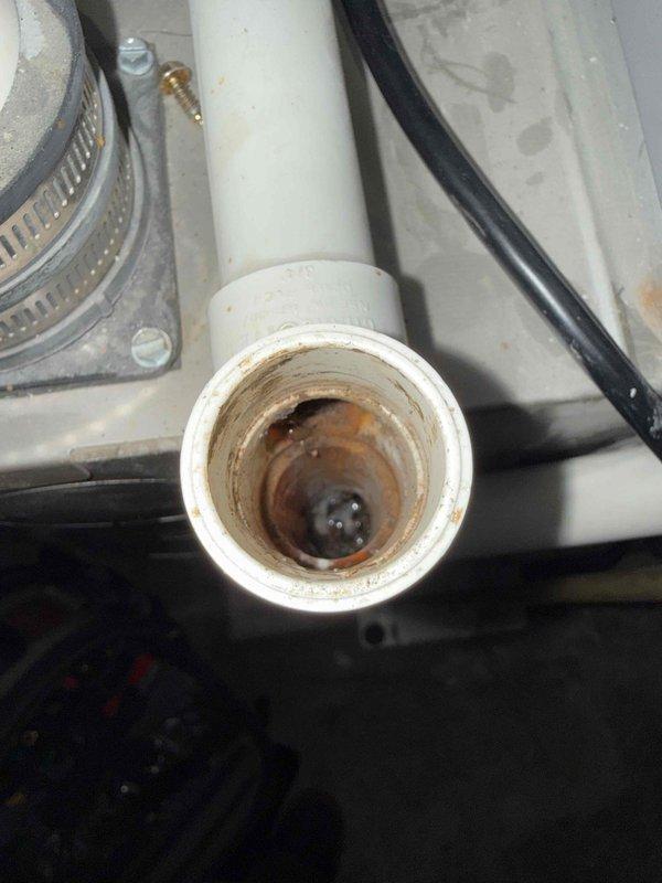 Responded to no cooling complaint on 10+ year old AC unit located in basement. Upon inspection, found blower wheel assembly operational but discovered significant rust and corrosion buildup inside condensate drain line, indicating long-term moisture accumulation and potential drainage issues. Documented equipment condition with photos showing blower assembly in clean operational state and severely corroded PVC drain pipe interior. Advised property owner of findings and recommended drain line cleaning and system evaluation to prevent future drainage problems that could lead to water damage or system shutdown.
