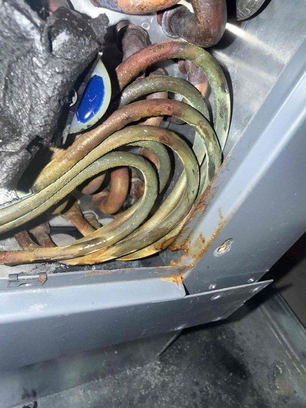 Responded to no cooling complaint on second floor AC unit, approximately 4 years old. Upon inspection, discovered extensive corrosion and rust on evaporator coil assembly, indicating active refrigerant leak. The coil exhibited significant oxidation with greenish-yellow to brown discoloration and deterioration of metal components. Conducted visual leak search as supervisor-level diagnostic. Documented condition with photographs showing compromised coil integrity and corroded fittings. Outdoor condensing unit inspected and photographed showing standard residential installation on concrete pad with proper clearances. Advised homeowner that evaporator coil replacement required due to extent of corrosion and refrigerant leak, which is causing loss of cooling capacity and warm air delivery from system.
