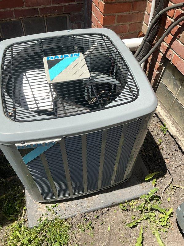 Completed Gold AC inspection on residential property with two 4-year-old Daikin units. During inspection of outdoor condensing unit, discovered failed capacitor with severely corroded and burned terminals, which was identified as the source of the loud noise reported by homeowner. Capacitor exhibited heavy oxidation, charring, and terminal deterioration indicating electrical failure. Removed defective capacitor and replaced with new component. Inspected refrigerant lines, electrical connections, and conduit routing along exterior wall. Verified proper unit placement on concrete pad and checked coil location in basement. Tested system operation after capacitor replacement to ensure noise was eliminated and unit returned to normal function. Both AC units inspected and documented with photos for service records.