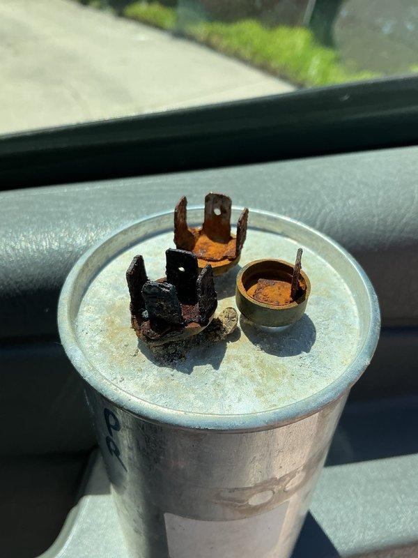 Completed Gold AC inspection on residential property with two 4-year-old Daikin units. During inspection of outdoor condensing unit, discovered failed capacitor with severely corroded and burned terminals, which was identified as the source of the loud noise reported by homeowner. Capacitor exhibited heavy oxidation, charring, and terminal deterioration indicating electrical failure. Removed defective capacitor and replaced with new component. Inspected refrigerant lines, electrical connections, and conduit routing along exterior wall. Verified proper unit placement on concrete pad and checked coil location in basement. Tested system operation after capacitor replacement to ensure noise was eliminated and unit returned to normal function. Both AC units inspected and documented with photos for service records.