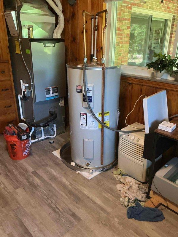 Completed installation of 50-gallon electric water heater in residential utility room. Unit was properly positioned on wooden platform with metal drain pan installed at base per code requirements. Connected copper supply lines to inlet and outlet ports with appropriate fittings and installed drain line from pan to ensure proper drainage in event of tank failure. All plumbing connections were secured and tested for leaks. Verified electrical connections and proper grounding of unit. System was filled, tested, and confirmed operational with no leaks detected at any connection points.