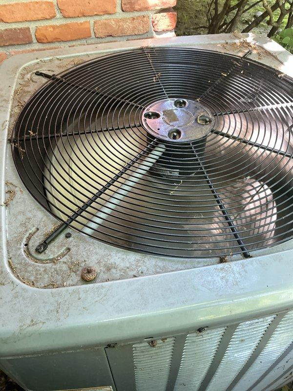 Completed routine summer air conditioning tune-up on a 2-3 year old system with indoor unit located in basement and outdoor condenser unit positioned against exterior brick wall. Performed comprehensive maintenance inspection including cleaning condenser coils, checking refrigerant levels, testing electrical connections, verifying proper airflow through fan assembly, and inspecting condensate drain lines. System operating within normal parameters with no issues identified; unit showing typical outdoor weathering but functioning properly for continued reliable cooling performance.