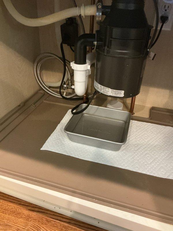 Responded to active leak under kitchen sink in 26-year-old residential property. Upon inspection, identified compromised connection at garbage disposal drain assembly and deteriorated P-trap seal causing water intrusion into cabinet base. Disassembled existing drain configuration, replaced P-trap assembly with new PVC components, and re-secured disposal discharge connection with proper gasket seal. Tested all connections under full water pressure to verify leak elimination. Additionally, installed new quarter-turn shutoff valves in basement to replace original gate valves showing age-related wear. All plumbing fixtures tested and confirmed operational with no additional leaks detected throughout property.