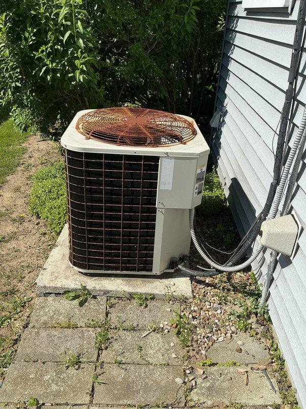 Performed estimate for air conditioning system replacement at residential property. Unit evaluated showed failing contactor and low R22 refrigerant levels, with equipment age exceeding 10 years. Outdoor condenser unit located on concrete pad adjacent to house with evaporator coil installed in basement. System inadequately cooling living space due to component failure and refrigerant loss in aging equipment operating on phased-out R22 refrigerant. Documented existing installation with exterior condenser mounted on weathered concrete pad with electrical service running along exterior wall to main service panel. Provided comprehensive replacement options and recommendations for modern high-efficiency system upgrade with updated refrigerant technology.