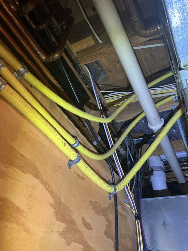Installed new thermostat wire from the HVAC unit to the thermostat location. Routed yellow flexible conduit through ceiling joists alongside existing plumbing and electrical infrastructure, securing it properly with fasteners to wooden structural members. Connected wiring to the Lennox heating system and verified proper operation of the thermostat control circuit.