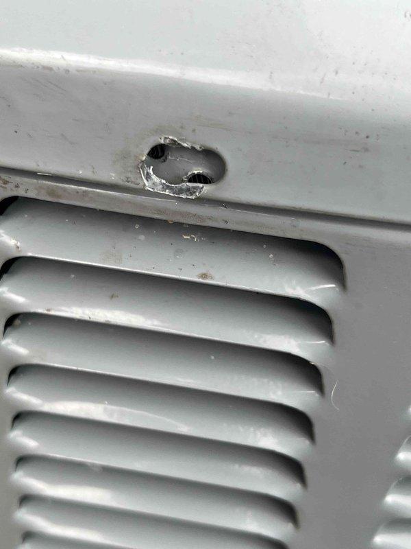 Responded to warranty service call for 3-year-old residential air conditioning system experiencing short cycling condition with approximately 5-second run intervals. Performed leak search inspection on evaporator coil assembly by manipulating and examining cooling fins as directed. Documentation photos reveal significant physical damage to exterior cabinet housing, including punctured opening with exposed metal and paint deterioration around damaged area. Ventilation louvers and fin assembly remain structurally intact despite cabinet damage.