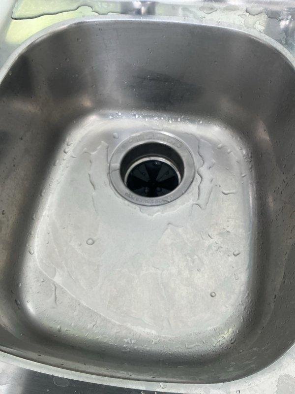 Responded to slow-draining kitchen sink in 30-year-old residence. Upon inspection, found stainless steel sink basin with visible mineral deposits and water spotting, indicating drainage issues isolated to kitchen area only. Accessed under-sink plumbing system and inspected garbage disposal unit, drain lines, and PVC waste connections. Identified partial obstruction causing reduced flow rate over 2-3 day period. Cleared blockage from drain line using appropriate mechanical methods. Verified proper drainage function of disposal unit and confirmed all connections secure with no leaks present. Tested system flow rate and restored full drainage capacity to kitchen sink.