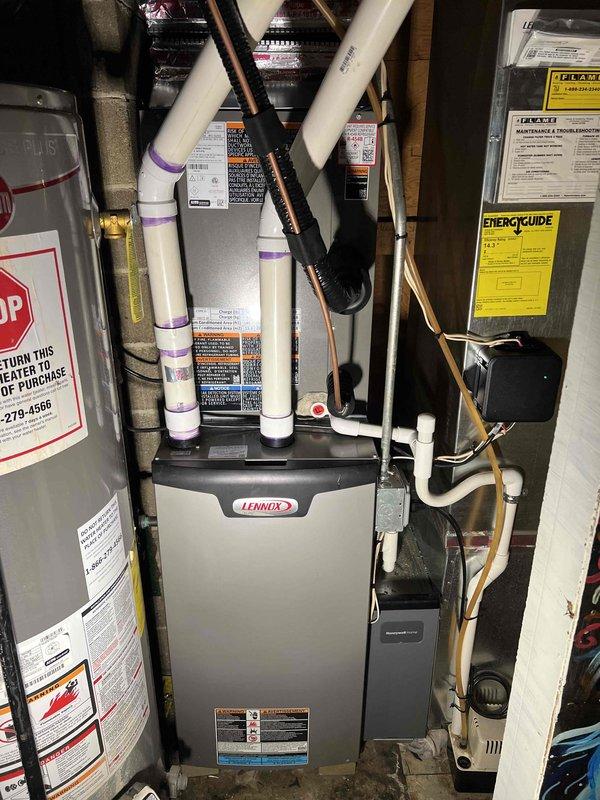 Successfully completed installation of a 2.5-ton Lennox air conditioning system with evaporator coil at residential property. Positioned new condenser unit on rubber isolation pad with gravel base against rear exterior brick wall, installed electrical disconnect box and conduit with proper wiring connections to building exterior. Interior work included evaporator coil installation integrated with existing Lennox furnace system in mechanical room, with PVC condensate drainage lines and refrigerant line connections completed. Performed electrical reconnection of all components, tested system operation, and verified proper refrigerant charge and airflow. Permits requested for mechanical, electrical, and air conditioning work per local code requirements. All equipment installed per manufacturer specifications with proper clearances maintained, system fully operational upon completion.