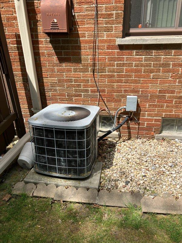 Conducted on-site evaluation for air conditioning system replacement at residential property. Assessed existing outdoor condensing unit positioned on concrete pad along exterior brick wall, noting copper refrigerant lines, electrical disconnect box, and overall system configuration. Documented indoor air handler and ductwork assembly in basement mechanical room to determine compatibility requirements for replacement equipment and provide comprehensive replacement estimate.