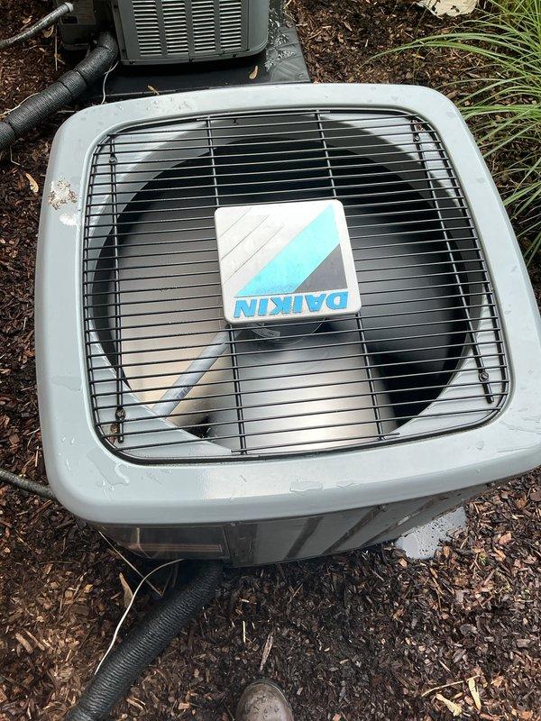 Completed comprehensive AC inspection on multi-unit residential system with 4-year-old Daikin equipment. Inspected outdoor condenser units positioned in landscaped area with mulch bedding, verified proper fan operation, checked refrigerant lines and electrical connections, and documented equipment condition with protective grilles intact and functioning normally. Air handler/coil located in basement was assessed, and all components found to be operating within normal parameters with no immediate service needs identified.