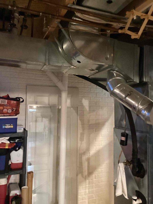 Conducted comprehensive site evaluation for full HVAC system replacement at residential property. Assessed existing outdoor air conditioning condenser unit positioned on concrete pad adjacent to brick exterior wall, noting current electrical disconnect configuration and conduit routing. Evaluated interior furnace and air handler installation in basement mechanical room, including existing ductwork layout with galvanized metal supply and return plenum connections. Documented current system specifications, electrical service requirements, and structural mounting considerations for equipment replacement. Photographed outdoor condenser unit showing utility markings on ground and current electrical connections, as well as basement air handler with flexible and rigid ductwork distribution system mounted to painted masonry wall. Prepared detailed measurements and specifications for new furnace and air conditioning system installation, accounting for existing infrastructure, clearance requirem
